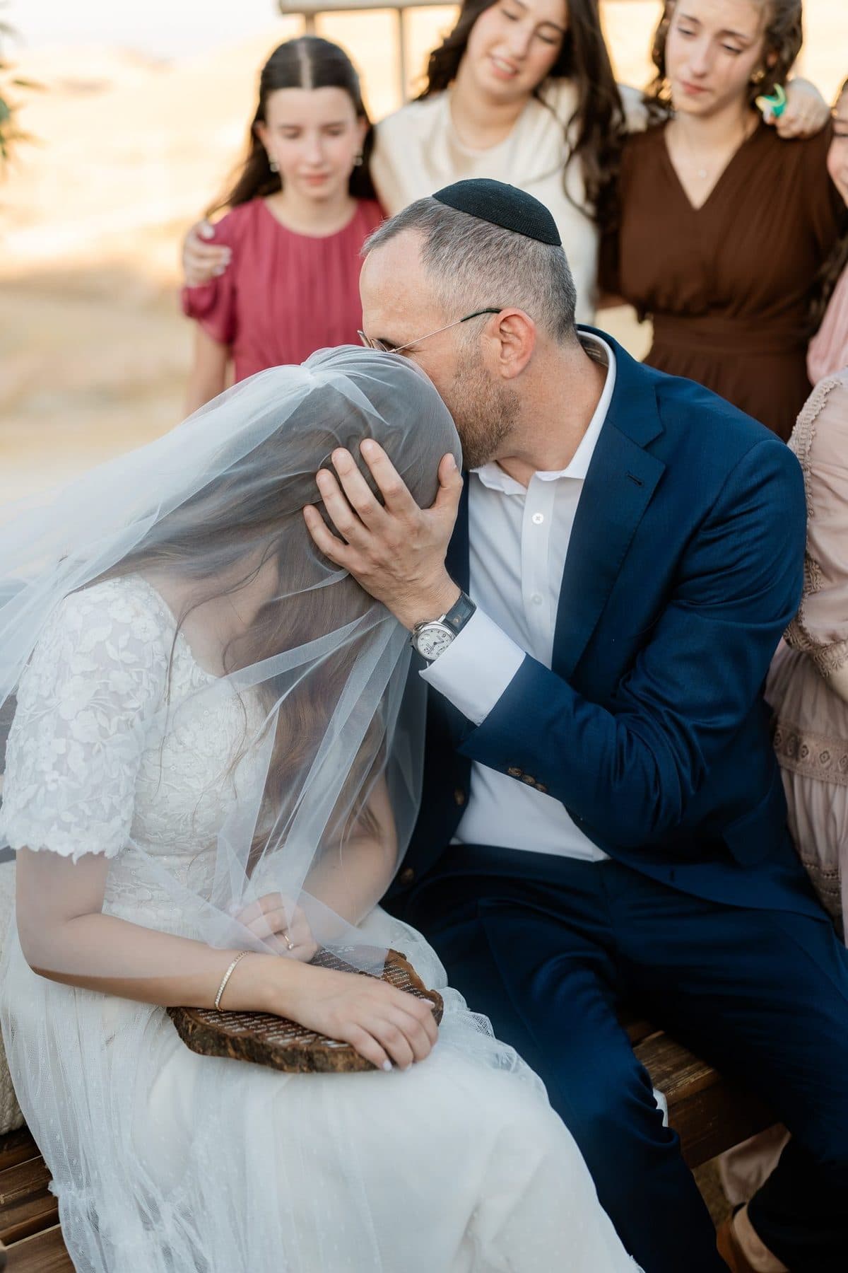 אב מנשק את ראש הכלה, שמכוסה בהינומה